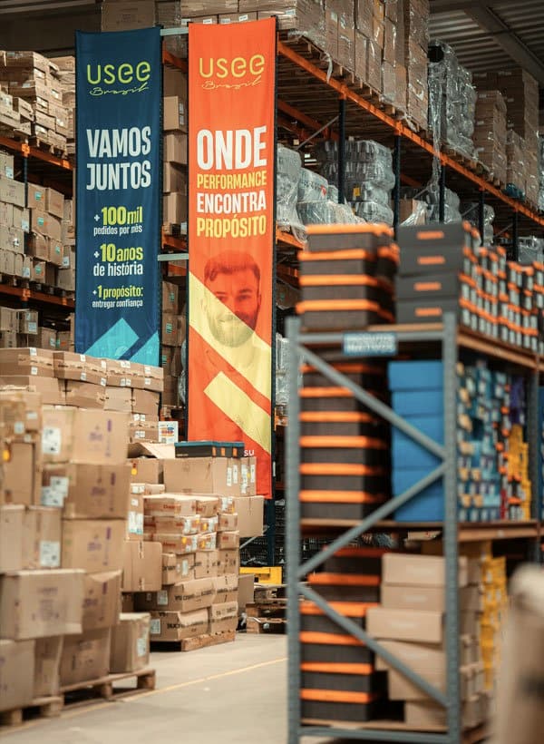 Corredor do centro de distribuição da Usee Brasil, com prateleiras de estoque e caixas para expedição